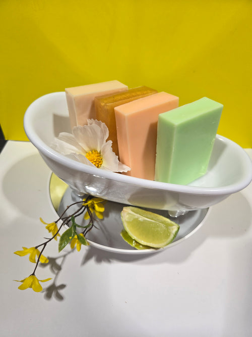 White ceramic bowl with colorful soap bars and decorative flowers on a yellow background